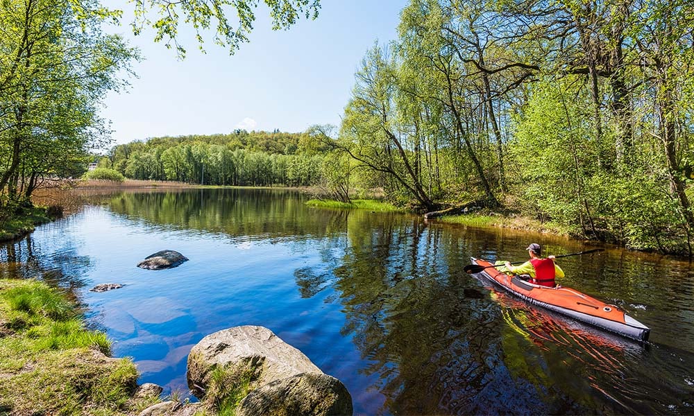 Person paddlar Advanced Elements luftkajak i naturskön miljö – uppblåsbar kajak på stilla vatten