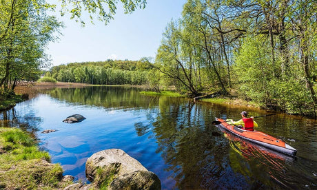 Person paddlar Advanced Elements luftkajak i naturskön miljö – uppblåsbar kajak på stilla vatten