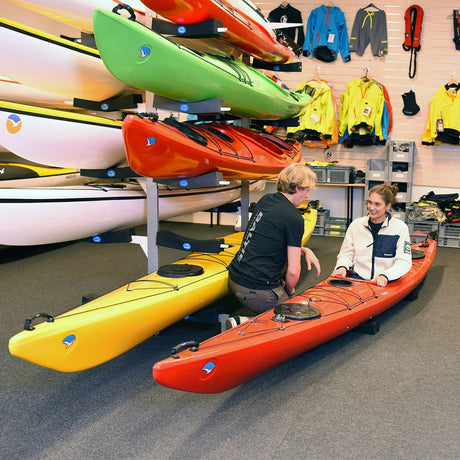 En kund provar en röd Seabird Expedition-havskajak inne i en butik, med en försäljare i bakgrunden.