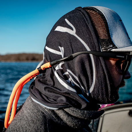 En man bär en svart buff/ansiktsmask, solglasögon (Leech) och en tjock orange flytsnodd/glasögonsnöre. Perfekt skydd för fiske på vattnet