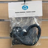 Förpackad paddelsäkring/leash från Vidda. Svart spiralsnöre med karbinhake och kardborreband för att säkra paddeln till kajaken