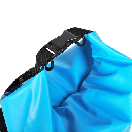 Närbild på stängningen av en ljusblå, vattentät Vidda drybag. Visar svart rulltopp och spänne för tät försegling